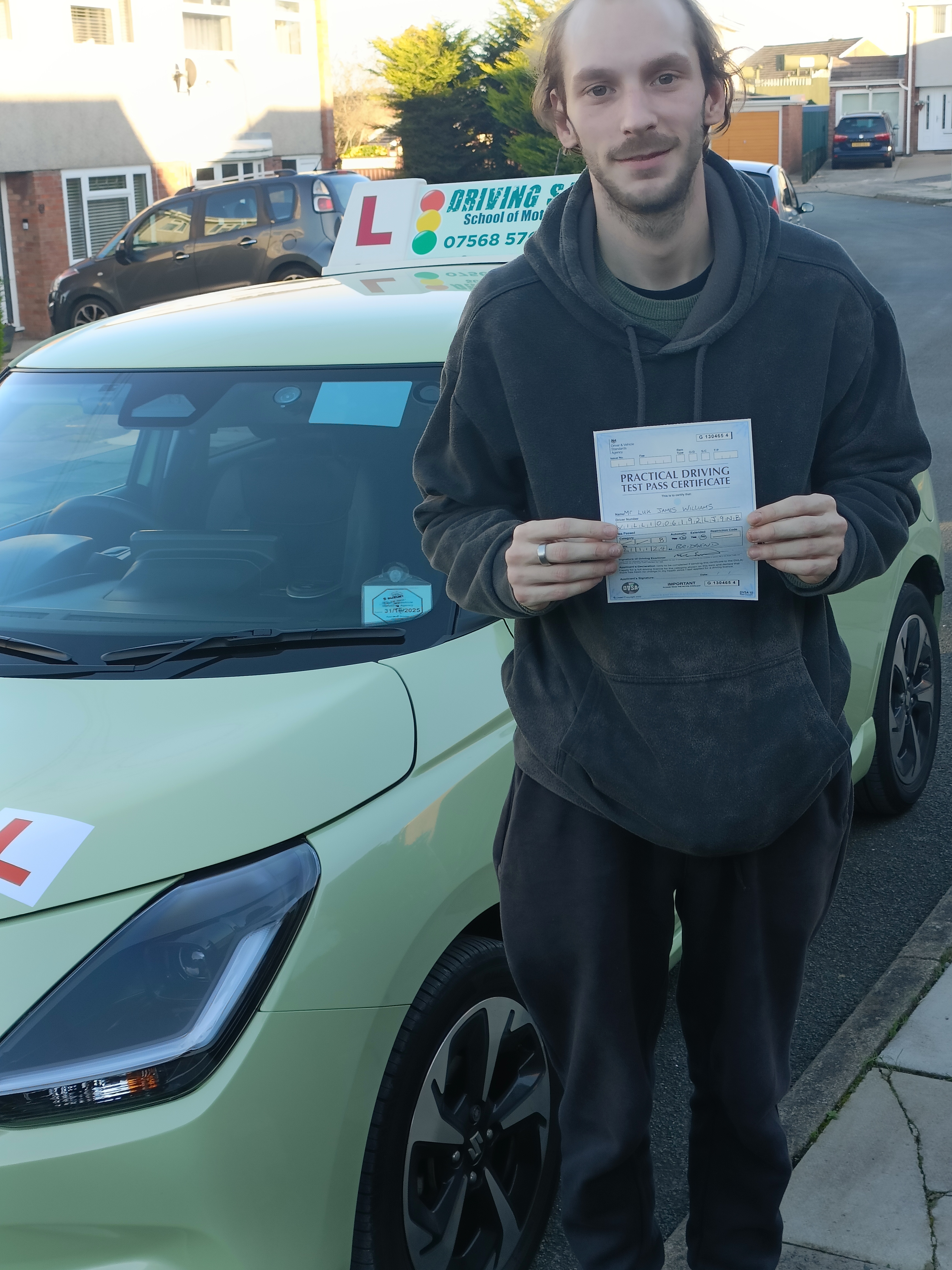 Learner driver smiling and holding a driving test pass certificate in Bridgend after lessons with Driving Safe School of Motoring